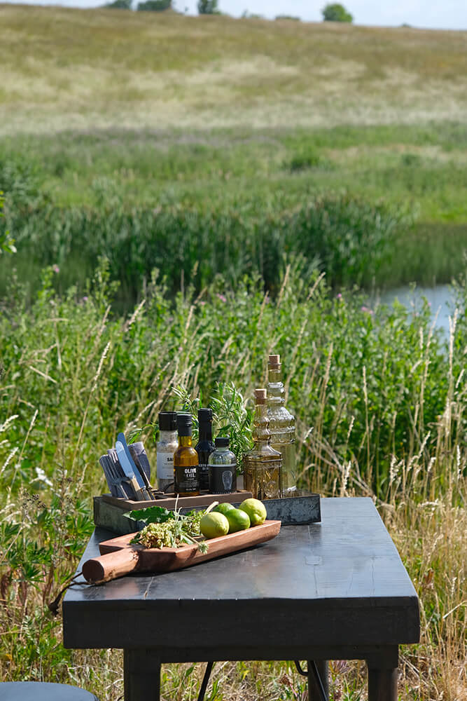 et picnicbord med flasker olivenolie og en bakke med frugt